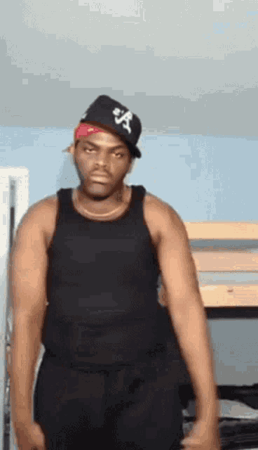 a man wearing a hat with the letter a on it is standing in front of a bunk bed