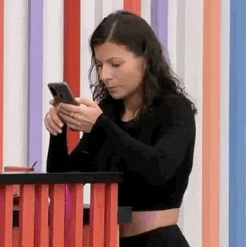 a woman is sitting at a table using her cell phone .