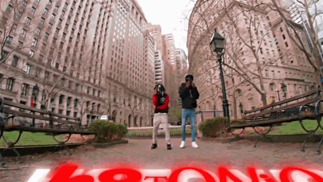 two men are standing in a park with a sign that says ' boston '