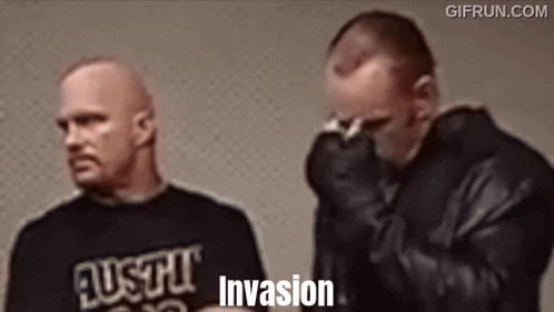 two men are standing next to each other and one of them is covering his face .