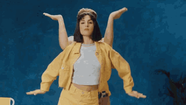 a woman in a yellow jacket is dancing with a man behind her