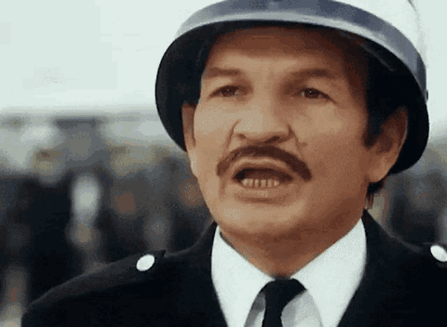 a man with a mustache is wearing a helmet and making a funny face
