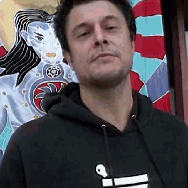 a man wearing a black hoodie with the letter i on the front