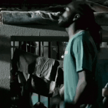 a man in a blue shirt stands in a dark room