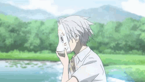 a boy is holding a mask in front of his face in a field .