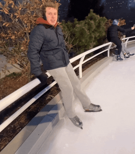 a man is sitting on a railing on a ice rink
