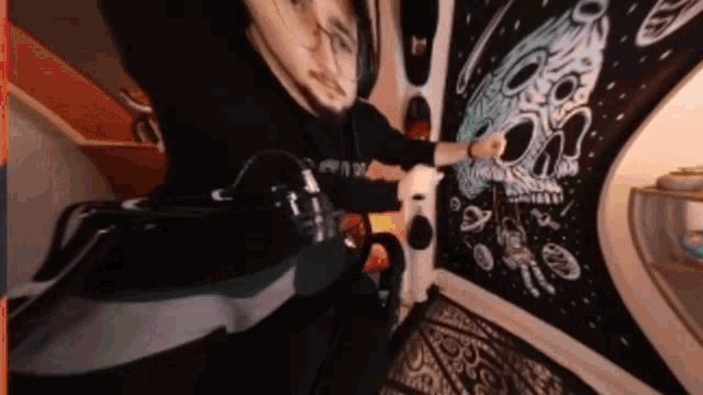 a man is standing in front of a wall with a skull on it