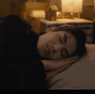 a woman is sleeping with her eyes closed and her head resting on her hands