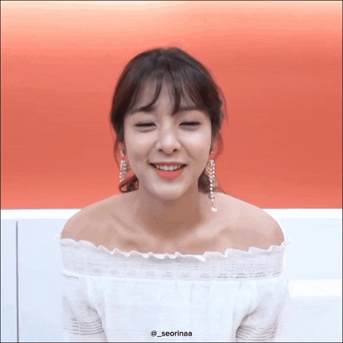 a woman wearing a white off the shoulder top and earrings has the name seorinaa on her shoulder