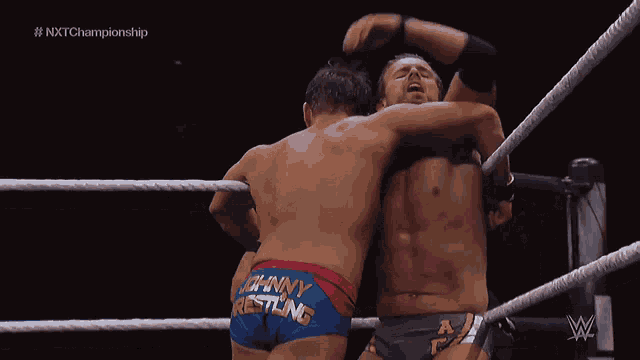 two men are wrestling in a ring and one of them has johnny wrestling on his shorts