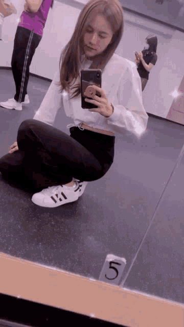 a woman taking a picture of herself in front of a mirror with a number 5 on it