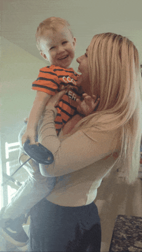 a woman is holding a little boy who is wearing a shirt that says ' tiger ' on it
