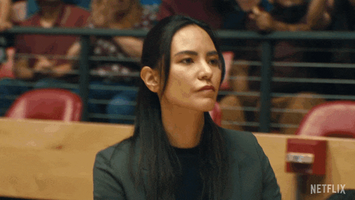 a woman is sitting in a stadium with a netflix logo in the corner
