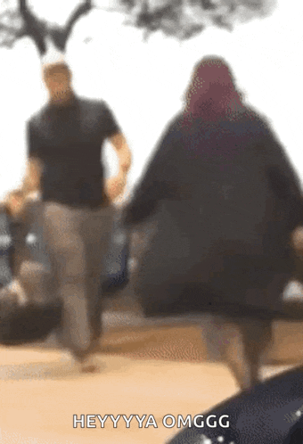 a blurry picture of a man and a woman walking with the caption heyyyya omgg