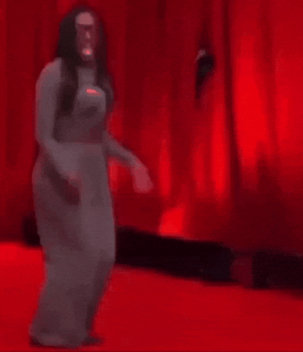 a man is laying on a red carpet in front of a red curtain .