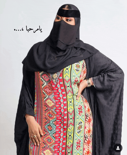 a woman wearing a black veil and a colorful dress with arabic writing on the bottom