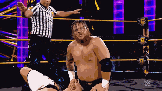 a wrestler in a wrestling ring with a referee standing behind him
