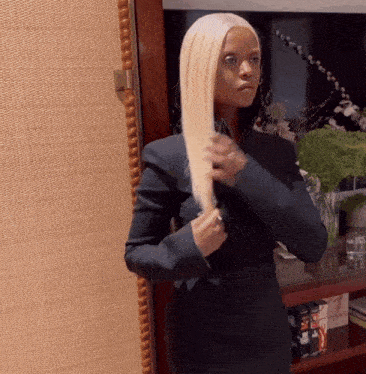 a woman with blonde hair is standing in front of a mirror