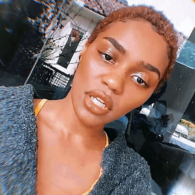 a close up of a woman 's face with a gray sweater on