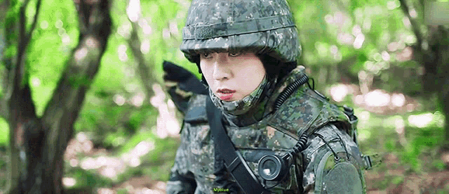 a soldier is standing in the woods wearing a helmet and holding a gun .