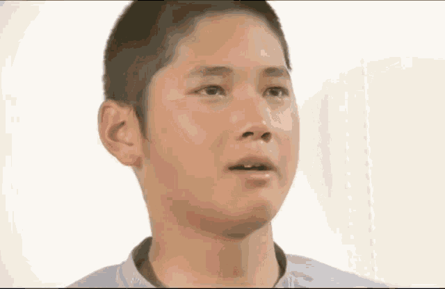 a close up of a young boy 's face with a shaved head .