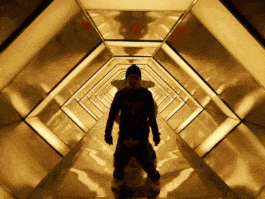 a man in a black sweatshirt with an eagle on it stands in a hallway