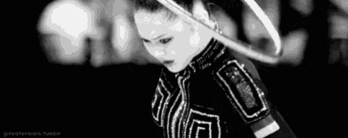 a black and white photo of a female gymnast with a hula hoop .