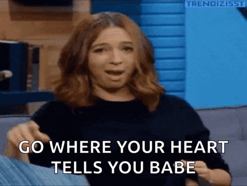 a woman is sitting on a couch with her mouth open and says go where your heart tells you babe .