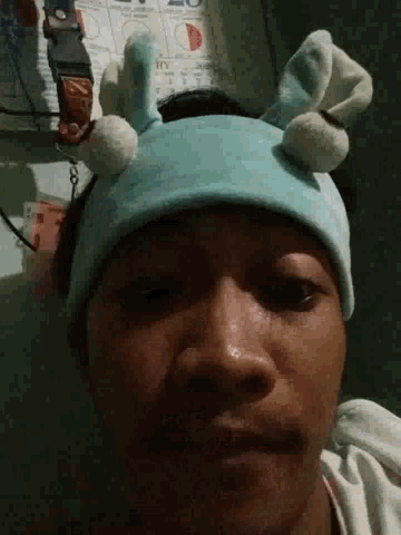 a close up of a person wearing a blue hat with white pom poms