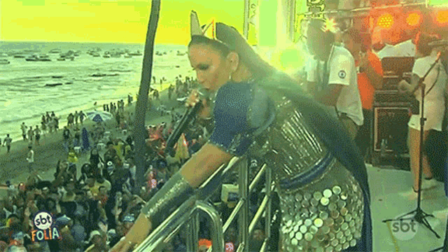 a woman singing in front of a crowd with sbt folia written on the bottom