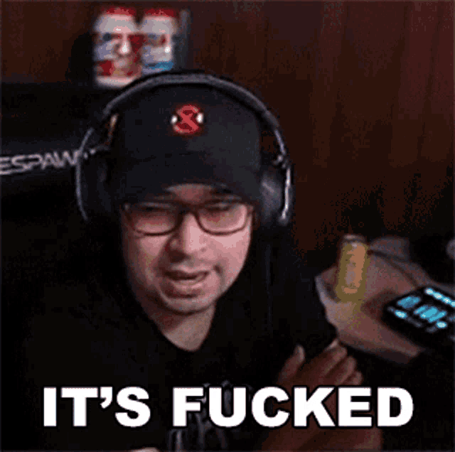 a man wearing headphones and a hat says `` it 's fucked '' while sitting in front of a computer .