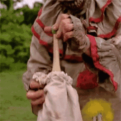 a person in a clown costume is holding a stick in their hand .