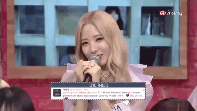 a woman is holding a microphone in front of a screen that says live tweets on it