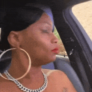 a woman in a car wearing hoop earrings and a chain necklace