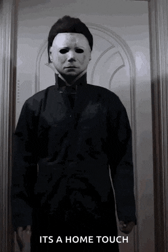 a man in a mask is standing in front of a door with the words " it 's a home touch " on the bottom