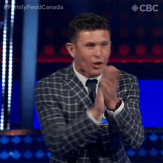 a man in a suit and tie is clapping his hands on a stage .