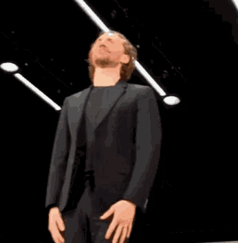 a man in a suit is standing on a stage with his hair in the air .