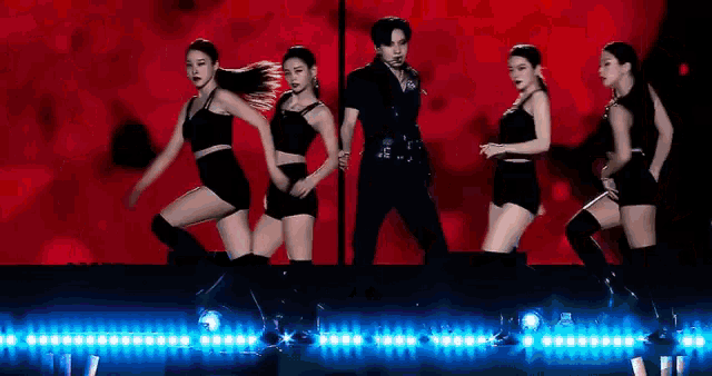 a group of dancers are performing on a stage with a red background