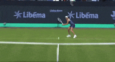 a woman is playing tennis in front of a banner that says libema