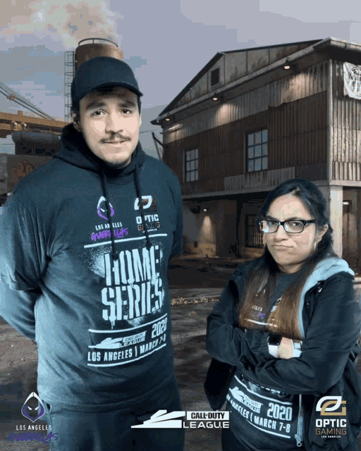 a man and a woman are posing for a photo in front of a call of duty league poster