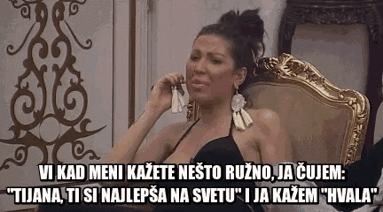 a woman in a black dress is sitting in a chair and talking on a phone