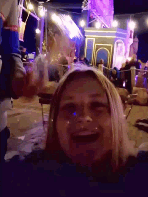 a woman is smiling in front of a crowd at night
