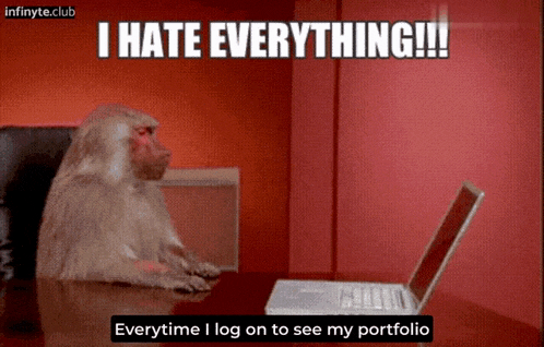 a monkey sits at a desk in front of a laptop and says i hate everything