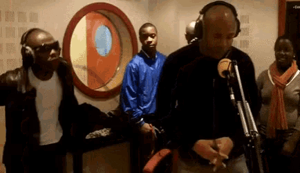 a man wearing headphones stands in front of a microphone in a studio