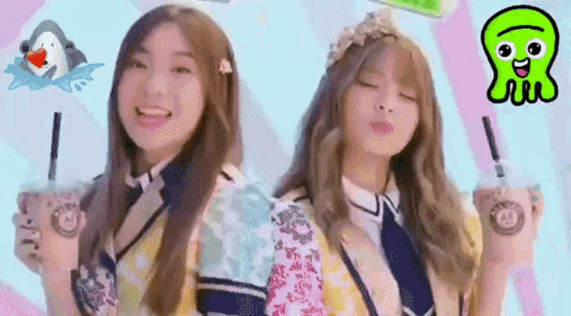 two girls are standing next to each other holding cups of drinks .