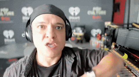 a man wearing headphones stands in front of a wall that says iheartradio