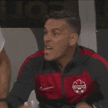 a man wearing a red and black jacket with a canadian flag on it is laughing .