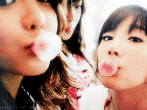 a girl blowing a pink bubble with the website weibo.com visible in the corner