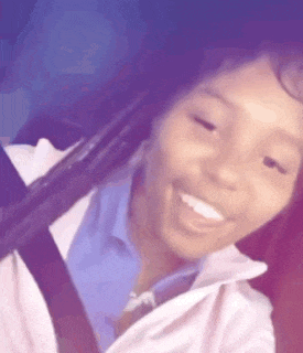 a woman is smiling while sitting in a car with a seat belt on .