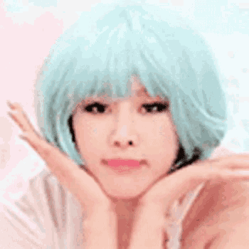 a woman wearing a light blue wig and a white shirt is making a funny face .